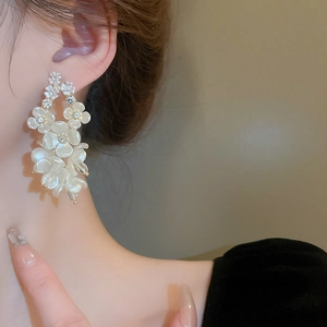 Detailed view of multilayer floral earrings with pearls and rhinestones on female model
