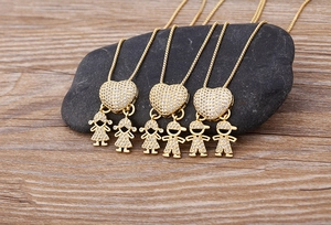 Dettaglio macro di ciondoli a cuore placcati oro 18k con charms bimbi su catena box