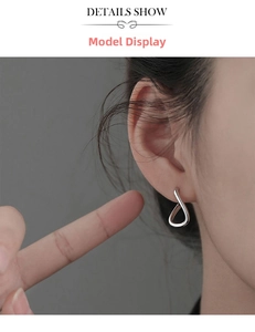 Gros plan sur une boucle d'oreille minimaliste en argent torsadée en forme de U