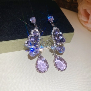 Close-up of butterfly earrings with purple teardrop crystals and silver needles