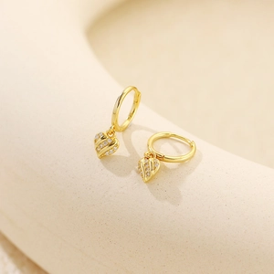 Macro shot of gold heart hoop earrings with striped textures and sparkling zircons