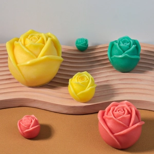 Detail van roosvormige geurkaarsen in verschillende maten en kleuren op een houten blad