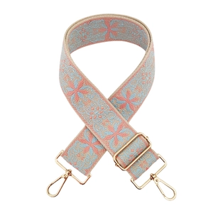 Close-up of jacquard woven bag strap with light blue pattern and gold hardware