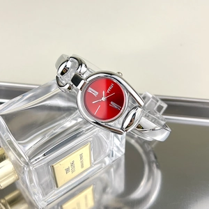 Detail of red sunray dial watch with silver horsebit bracelet on luxury background