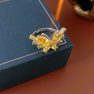 Gros plan d'une bague papillon argentée avec cristaux jaunes sur boîte en cuir bleu