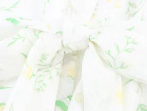 Detailed macro shot of floral embroidery and bow detail on the V-neck white dress