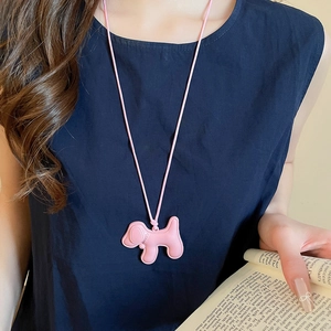 Gros plan d'un collier pendentif chiot rose porté sur un fond de vêtement bleu foncé