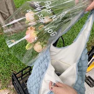 Close-up of light blue bubble textured tote bag on a bicycle basket with fresh flowers