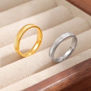 Funkelnde Wellenmuster-Ringe aus Titanstahl in Gold und Silber auf einer Schmuckbox
