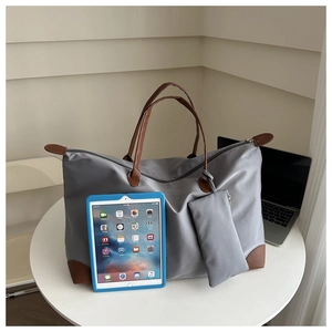 Large gray oxford tote bag set with brown handles and a small pouch on a white desk