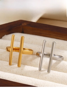 Detailaufnahme minimalistischer H-förmiger Ringe in Gold und Silber in einer Schmuckschatulle