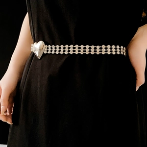 Detail der mehrlagigen Strass-Taillenkette mit silberner Herzschnalle auf schwarzem Kleid