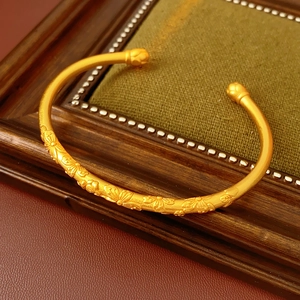 Detailed close-up of vintage gold-plated cuff bracelet with floral leaf engraving