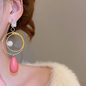 Dettaglio di orecchini di lusso con perla e goccia rosa con zircone quadrato su modella donna