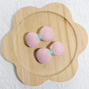 Gros plan de nœuds roses tricotés avec ruban vert sur un plateau en bois fleuri