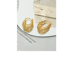 Macro view of gold-plated hollow mesh hoop earrings on a reflective mirror surface