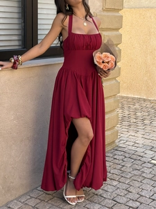 Detail of dark red halter neck maxi dress with side slit in elegant outdoor setting