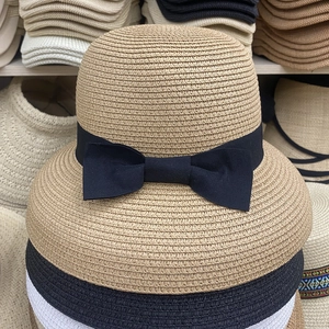 Detail of stacked summer straw sun hats in khaki and black with ribbon bow decor