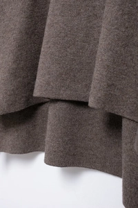 Close-up of brown knit fabric showing the drape and detailed texture of the hemline