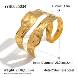 Detail view of gold stainless steel bangle with irregular liquid wave texture and wide cuff