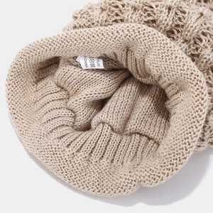 Detail of beige acrylic knitted fabric showing soft texture and high-quality edge stitching