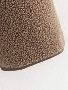 Close-up of brown fleece jacket texture showing premium curly wool fabric and hem detail
