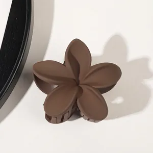 Macro view of matte mocha flower hair claw clip with smooth round petals on plain background