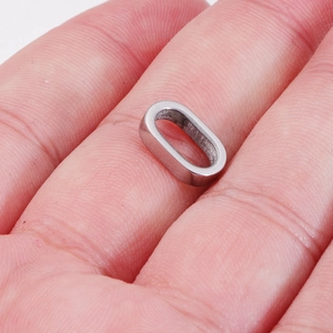 Polished silver oval stainless steel pendant connector held between fingers for DIY jewelry