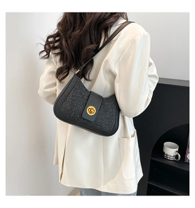 Detail of black underarm bag with gold twist lock on woman in beige blazer