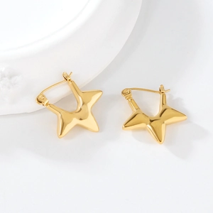 Close-up of chunky gold pentagram earrings with high-shine mirror finish on stone tray