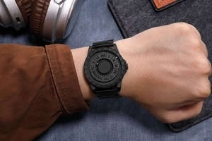 Detail of matte black magnetic ball watch with Roman numerals on a model's wrist