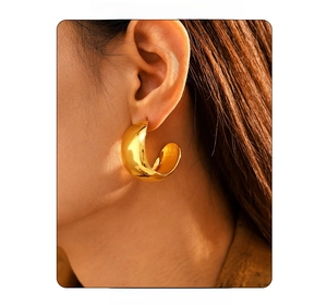 Close-up of golden chunky C-shaped hoop earrings with a mirror-polished finish