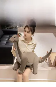 Close-up of a large soft grey plush dinosaur toy sitting on a cozy living room sofa