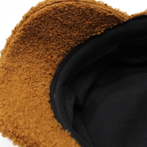 Detailed view of brown teddy fleece exterior and black lining of the warm winter hat