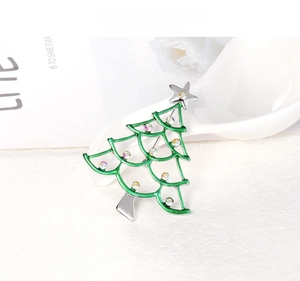 Detail view of a green enamel Christmas tree brooch with colorful rhinestones on a white base