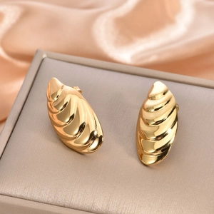 Detailed macro shot of gold spiral texture earrings on elegant champagne silk fabric
