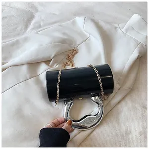 Detail of black glossy cylindrical bag with silver horseshoe handle and gold chain strap
