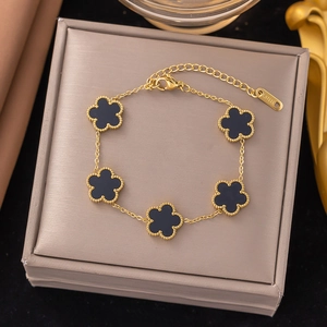 Macro shot of 5 black clover motifs on a gold stainless steel chain over a jewelry box