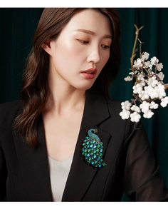 Detailed close-up of a colorful peacock brooch with rhinestones on a black suit jacket