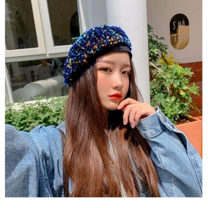 Close-up of blue sequin beret hat with shimmering texture worn by model in street style