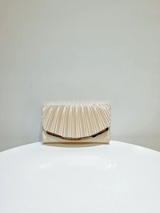 Detailed view of champagne gold pleated clutch with metallic curved edge for evening events
