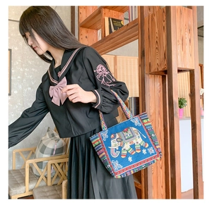 Detail of blue canvas bag with elephant embroidery and ethnic woven handle straps