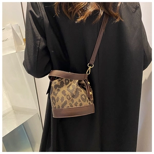Detail of leopard print bucket bag with brown leather trim worn by a model in a black blazer