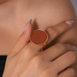 Gros plan d'une bague ronde en émail rouge-brun avec bordure métallique dorée