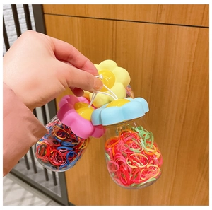 Three jars of colorful elastic hair bands with flower-shaped lids and hanging loops