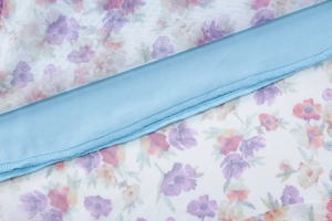 Detailed close-up of floral mesh fabric with light blue lining and delicate stitching