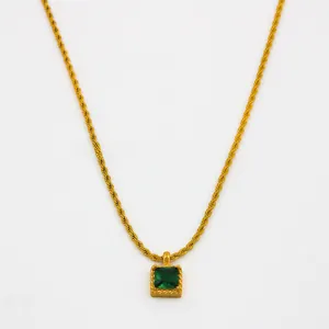 Détail macro d'un collier chaîne torsadée dorée avec pendentif carré en pierre verte