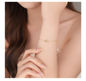 Close-up of a delicate gold chain bracelet with a sparkling eye-shaped charm and white zircon