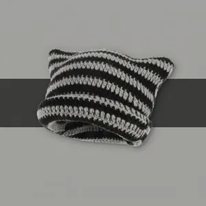 Détail du bonnet en tricot rayé noir et gris avec design d'oreilles de chat et texture en laine