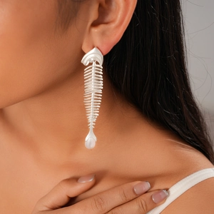 Close-up of silver fishbone earrings with zircons and pearls worn by a model
